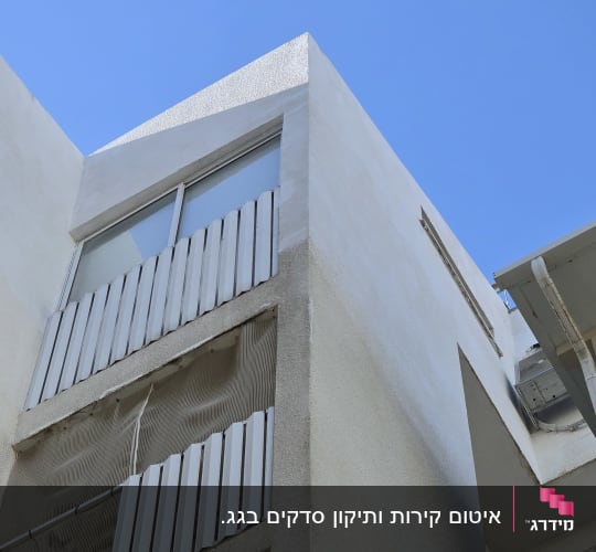 בניין עם חלונות ומזגן חיצוני על קיר לבן